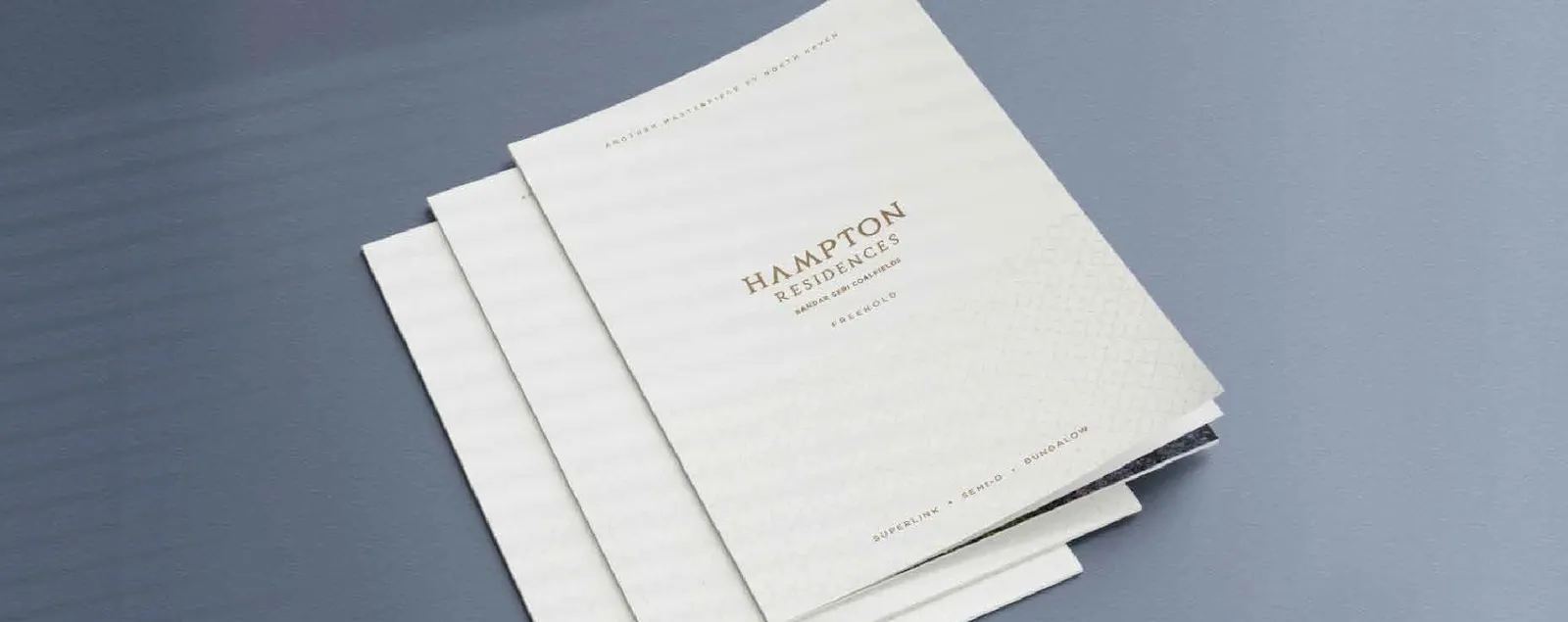 Hampton Residences brochures with foil-stamped covers, fanned on a table